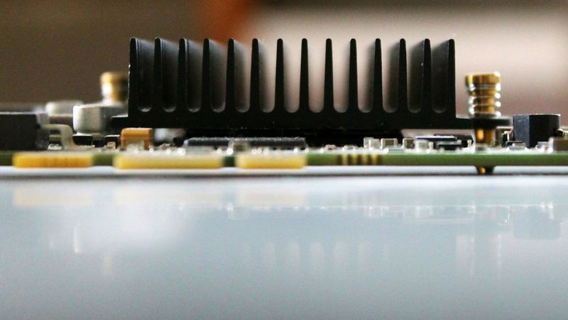 Kühlkörper einer Rechenkarte in Nahaufnahme, dahinter der Werkstattraum unscharf