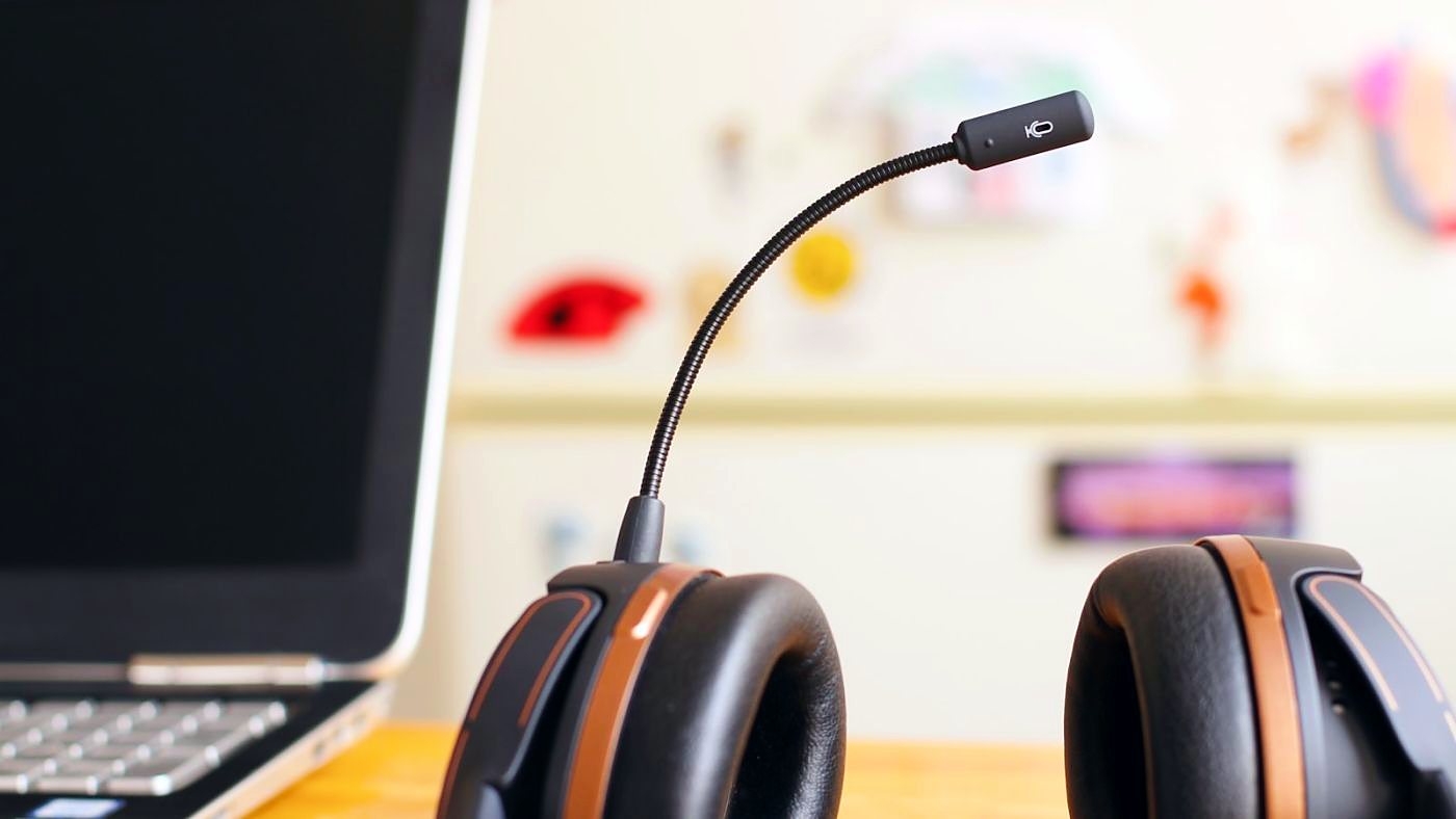 Headset neben einem Monitor an einem Arbeitsplatz bei gedämpftem Licht